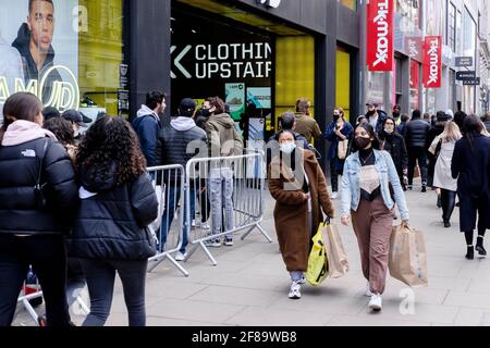 12 aprile 2021, acquirenti di Oxford Street, Londra a seguito dell'allentamento da parte del governo britannico delle restrizioni di Covid che consentono la riapertura di punti vendita non essenziali in Inghilterra. Le code si formarono fuori da molti negozi popolari, dato che i negozi accolsero i clienti dopo diversi mesi di chiusura. Foto Stock