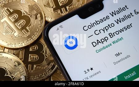 L'app Coinbase Wallet è visualizzata sullo schermo dello smartphone e si trova sul mazzo di monete di bitcoin. Concetto. Stafford, Regno Unito, 12 aprile 2021. Foto Stock