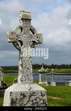 Primo piano di White Stone Celtic Cross a Graveyard in Irlanda Contro il cielo nuvoloso Foto Stock