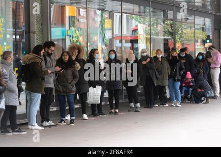 Londra, Regno Unito. 12 Aprile 2021. La foto scattata il 12 aprile 2021 mostra i clienti in coda per entrare in un grande magazzino a Londra, Gran Bretagna. In Inghilterra, tutti i negozi riaprono dal lunedì insieme ai parrucchieri, ai saloni di bellezza e ad altri servizi a contatto diretto. I ristoranti e i pub sono autorizzati a servire cibo e alcol ai clienti seduti all'aperto. Nel frattempo, palestre, terme, giardini zoologici, parchi a tema, le biblioteche e i centri comunitari possono aprirsi. Credit: Ray Tang/Xinhua/Alamy Live News Foto Stock