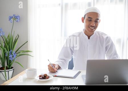 uomo d'affari musulmano che lavora con il computer portatile mentre si siede sulla scrivania Foto Stock