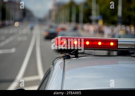 MINSK. BIELORUSSIA - LUGLIO 2016: Luci rosse lampeggianti sulla macchina di polizia sullo sfondo di una strada e di una folla di persone. Foto Stock