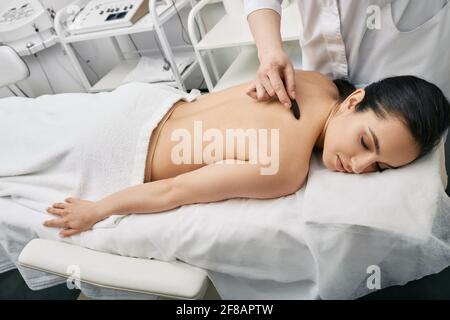 La donna delle brunette riceve il massaggio cinese del gouache per disintossicare il corpo Foto Stock