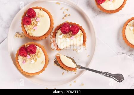 Piccola pasticceria a base di tartine con panna bianca, ricoperta di lamponi e mandorle Foto Stock