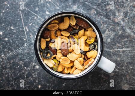 Mescolare le noci salate in tazza sul tavolo nero. Vista dall'alto. Foto Stock