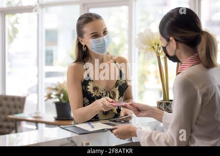 La receptionist consegna un passaporto ad un turista a te reception e reception di un ostello Foto Stock