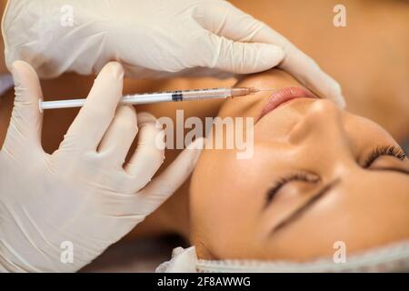 Cosmetologist che fa iniezione di bellezza del botox nelle labbra del woman con la siringa nel salone di bellezza Foto Stock
