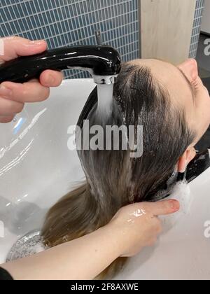 mani di parrucchiere che lavano i capelli di un cliente in un salone di bellezza Foto Stock