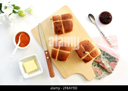 Panini caldi appena sfornati con burro e conserve su tagliere in legno. In composizione piana e in formato orizzontale. Foto Stock