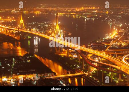 Vista aerea dei ponti sospesi e delle autostrade che si scambiano sul fiume Chao Phraya al crepuscolo, illuminanti sentieri attraverso i ponti. Thailandia. Foto Stock