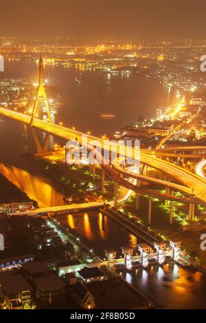 Vista aerea dei ponti sospesi e delle autostrade che si scambiano sul fiume Chao Phraya al crepuscolo, illuminanti sentieri attraverso i ponti. Thailandia. Foto Stock