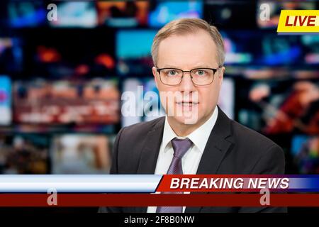 Un anchorman che riporta notizie dal vivo in studio TV. Sfondo di più schermi della sala di controllo delle trasmissioni. Concetto di giornalismo Foto Stock