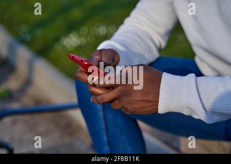 Primo piano delle mani nere che inviano un messaggio con uno smartphone. Navigazione sui social network. Concetto di tecnologia. Foto di alta qualità Foto Stock