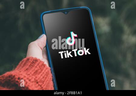 Podolsk, Ucraina - 29 marzo 2021: Donna che tiene smartphone con servizio sociale di Internet Tik Tok sullo schermo. Tiktok social network. Logo del CUR Foto Stock