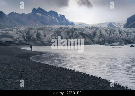 Passeggiate turistiche nella laguna glaciale in una giornata fredda e nuvolosa nell'Islanda meridionale. Il ghiacciaio cade in acqua. Tempo aspro, drammatico, nebboso. Foto Stock