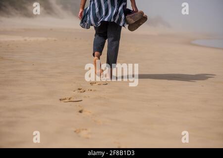 Donna che passeggiava da sola lungo la costa Foto Stock