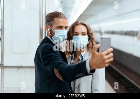 giovane coppia in maschere protettive che prende selfie in metropolitana. Foto Stock