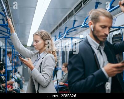 i passeggeri che utilizzano il proprio smartphone in metropolitana. Foto Stock