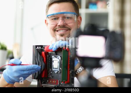 Blogger dimostra sulla riparazione della fotocamera della scheda del computer Foto Stock