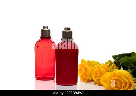 Bottiglie rosse per gel doccia e crema su fondo bianco. Vasetti in plastica leggeri. Su sfondo bianco. Ombre dure. Isolati. Concetto di regalo. Foto Stock