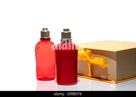 Bottiglie rosse per gel doccia e crema su fondo bianco. Vasetti in plastica leggeri. Su sfondo bianco. Ombre dure. Isolati. Concetto di regalo. Foto Stock