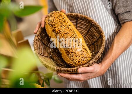 Mani maschili che tengono il cestino di pane Foto Stock