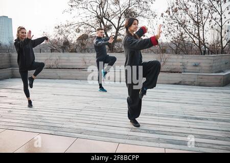 Vista laterale delle persone che fanno tai chi su una gamba Foto Stock