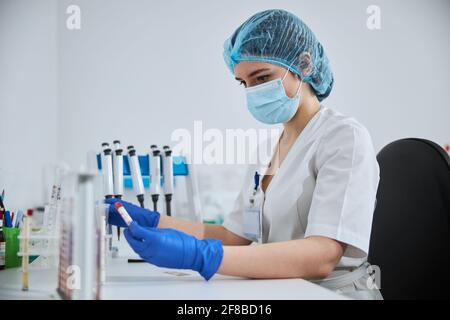 Tecnico di laboratorio serio che esamina un campione clinico in mano Foto Stock