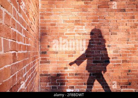 Ombra di un uomo su un muro di mattoni sfondo Foto Stock