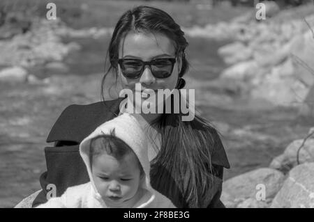 Bella scala di grigi ripresa di una donna asiatica elegante con lei Piccolo figlio all'aperto a Corsier Foto Stock