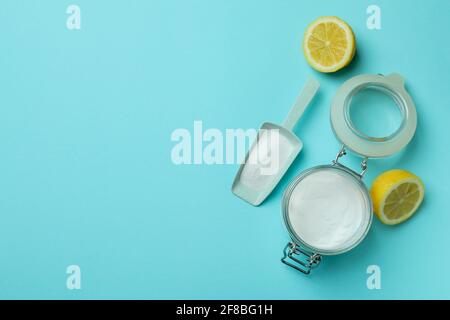 Sessola e vasetto con polvere acida e metà di limone su sfondo blu Foto Stock