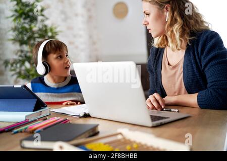 Il figlio disturba la mamma nell'ufficio domestico Foto Stock