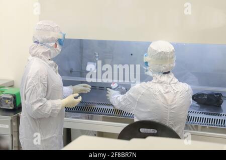 Gli scienziati di laboratorio indossano indumenti protettivi e svolgono ricerche mediche in un laboratorio scientifico. Foto Stock