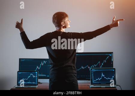 trader maschile di successo guardando monitor con grafico borsa o grafico Foto Stock