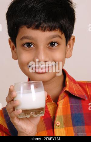 Mumbai, Maharashtra, India, Asia, 24 settembre 2006 - carino piccolo ragazzo indiano che tiene un bicchiere di latte che tiene il bicchiere in mano sano concetto Foto Stock