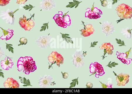 Modello trendy di primavera o estate fatto con diversi fiori volanti e foglie su sfondo verde menta pastello, bella disposizione floreale. Creative Minim Foto Stock