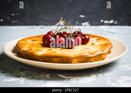Cheesecake tradizionale fatto in casa con ciliegie sul tavolo di legno. Messa a fuoco selettiva. Profondità di campo poco profonda. Foto Stock