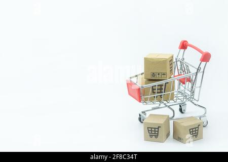 Concetto di shopping - cartoni o scatole di carta in rosso carrello di shopping su sfondo bianco. I consumatori di shopping in linea possono comprare dalla sede e dal servizio di consegna. Foto Stock