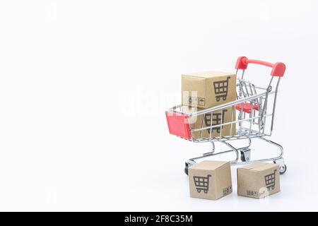 Concetto di shopping - cartoni o scatole di carta in rosso carrello di shopping su sfondo bianco. I consumatori di shopping in linea possono comprare dalla sede e dal servizio di consegna. Foto Stock