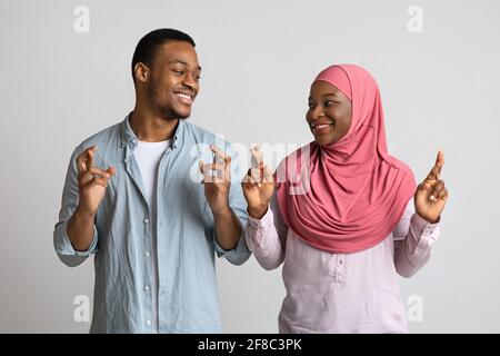 La coppia musulmana afroamericana con le dita ha attraversato sorridendo Foto Stock
