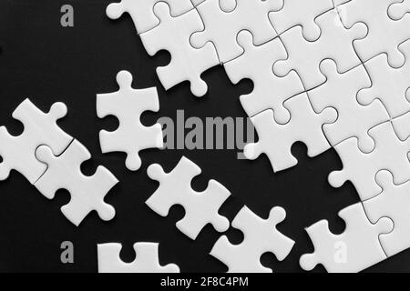 Pezzi di puzzle bianco incompiuto su sfondo nero Foto Stock