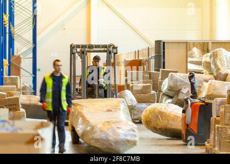 MOSCA, RUSSIA - 18 MARZO 2021 Warehouse worker che guida un carrello elevatore a forche pieno di merci all'interno del magazzino Foto Stock