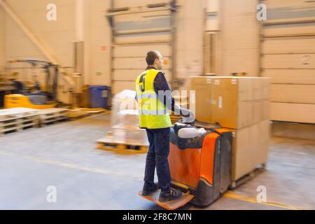 MOSCA, RUSSIA - 18 MARZO 2021 Warehouse worker che guida un carrello elevatore a forche pieno di merci all'interno del magazzino Foto Stock