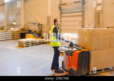 MOSCA, RUSSIA - 18 MARZO 2021 Warehouse worker che guida un carrello elevatore a forche pieno di merci all'interno del magazzino Foto Stock