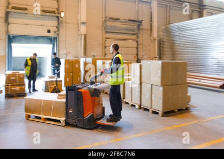 MOSCA, RUSSIA - 18 MARZO 2021 Warehouse worker che guida un carrello elevatore a forche pieno di merci all'interno del magazzino Foto Stock