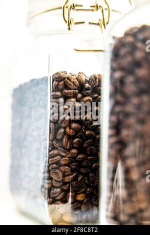 Shot verticale di vasetti di vetro riempiti di chicchi di caffè Foto Stock