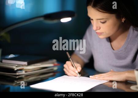 Donna seria firma forma nella notte a casa Foto Stock