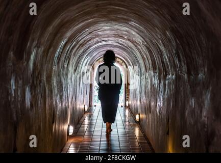 Donna che cammina attraverso il tunnel del Tempio Wat Umong Foto Stock