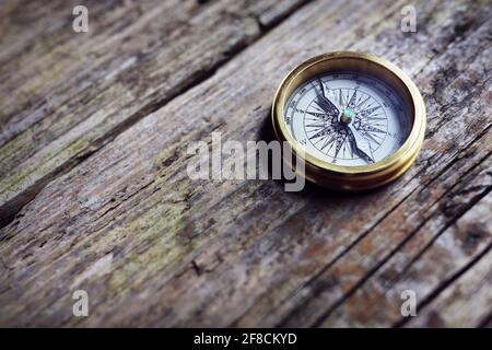 Antica bussola d'oro su legno di fondo concetto per direzione, viaggio, guida o assistenza Foto Stock