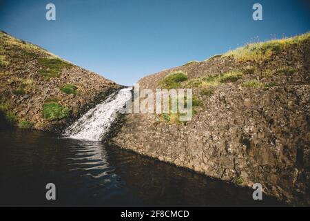 Piccole cascate atterra in una piscina scura su un basaltic Mesa Foto Stock